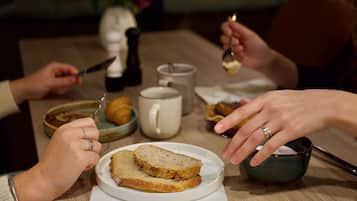 A dining table with a plate of bread, a mug, and a salt shaker.