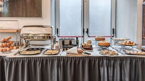 A breakfast buffet with various pastries, bread, and eggs.