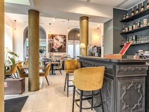 Uma área de bar com balcão, banquetas e prateleiras cheias de garrafas.