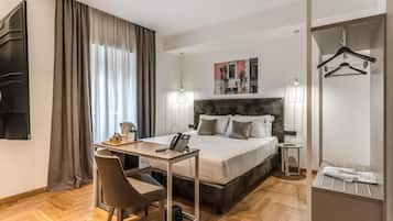 Habitación de hotel con cama, escritorio, silla y armario con perchero.