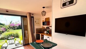 A compact kitchen with a dining area, a sliding glass door to a garden, and a sign indicating WIFI access. - Cosy studio overlooking the rock, 5 minutes from the beach on foot (Le Diamant)
