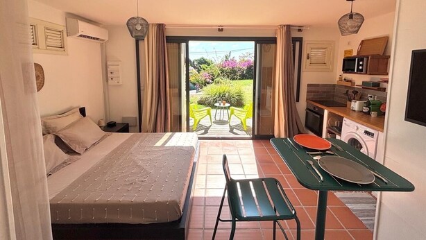 A compact room with a bed, a small dining table, and a kitchenette. - Cosy studio overlooking the rock, 5 minutes from the beach on foot (Le Diamant)