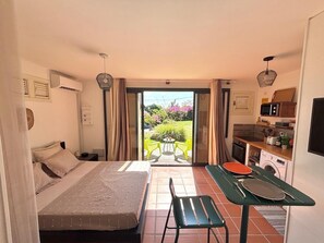 A compact room with a bed, a small dining table, and a kitchenette. - Cozy studio with a view of the cliffs, a 5-minute walk to the beach (Le Diamant)