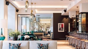 A modern interior with a sofa, bar area, and a large mirror. - Amerikalinjen (Oslo)
