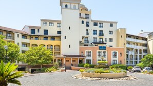 A multi-story hotel with a central courtyard, a dome on the top floor, and a sign reading "Island Club". - Island Club 410 (Cape Town)