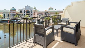 A balcony with wicker furniture overlooking a body of water and buildings with domed roofs. - Island Club 410 (Cape Town)