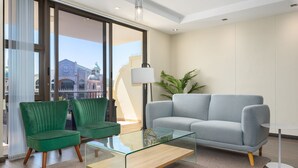 A modern living room with a glass coffee table, two green chairs, a grey sofa, and a lamp. - Island Club 410 (Cape Town)