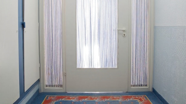 Eine Tür mit der Nummer 112, einem Schlüsselloch und einem kleinen Fenster.