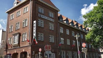 Ein mehrstöckiges Backsteingebäude mit dem Schild 'City Hotel'.