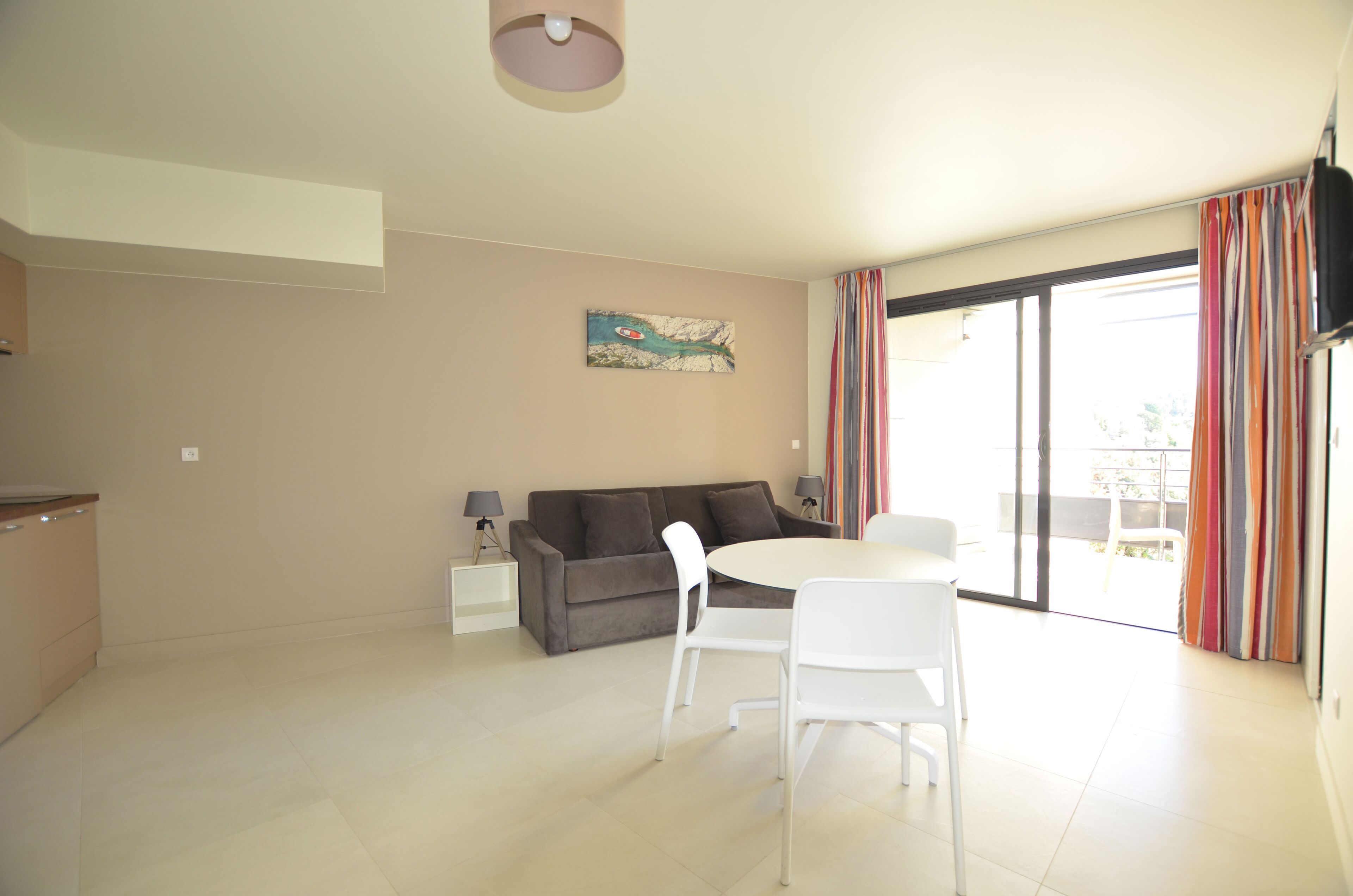 Una sala de estar moderna con un sofá gris, una mesa redonda blanca y un televisor montado en la pared.