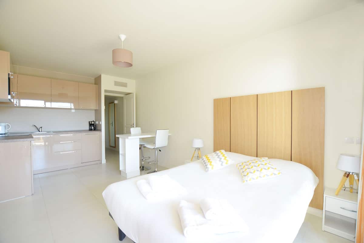 Una habitación de hotel moderna con una cama grande, un escritorio pequeño, una kitchenette y un baño.