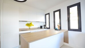 A modern kitchen with white cabinetry, a wooden countertop, and a built-in dishwasher.