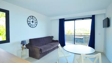 A modern living room with a sofa, a round table, and a clock on the wall.