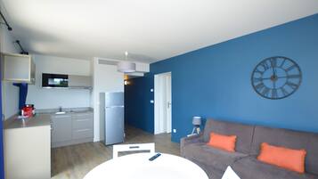 A modern living space with a kitchen, dining area, and a blue accent wall.