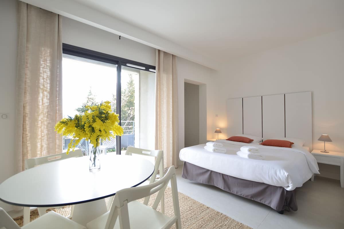 Una habitación de hotel moderna con una cama, mesitas de noche, una mesa redonda de comedor y sillas.
