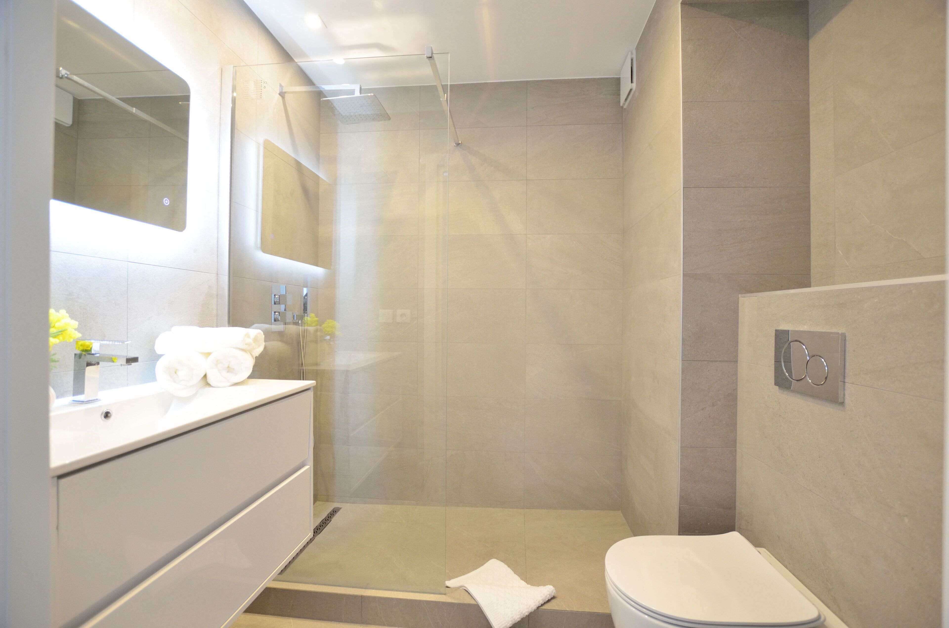 Une salle de bain moderne équipée d’une douche, de toilettes et d’un meuble-lavabo.