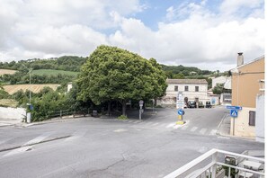 A street view with a large tree, buildings, and a clear sky.