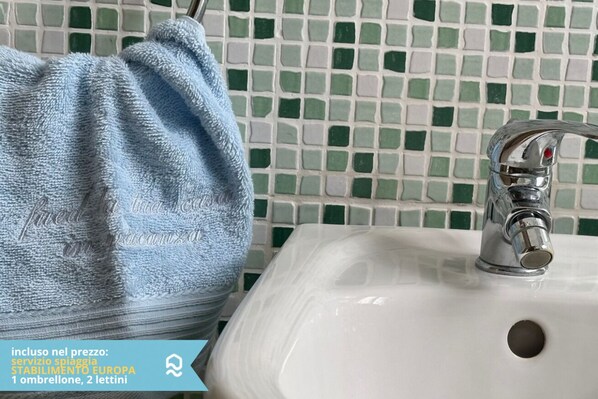 Une salle de bain avec un lavabo blanc, un robinet chromé et une serviette bleue.