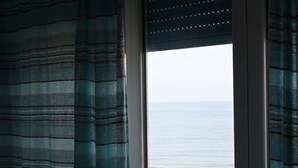 Una ventana con vistas al mar, cortinas y un marco de metal.