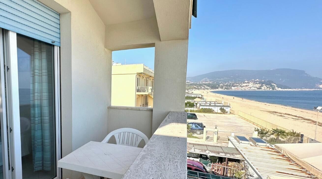 Ein Balkon mit Blick auf den Strand, einem Tisch und Stühlen.
