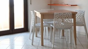 Un comedor con una mesa y sillas, una puerta corrediza de vidrio y un estante con objetos decorativos.