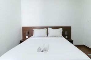 A neatly made bed with white linens and two rolled towels at the foot. - Kak Garden Inn by Zuzu (Kuta)