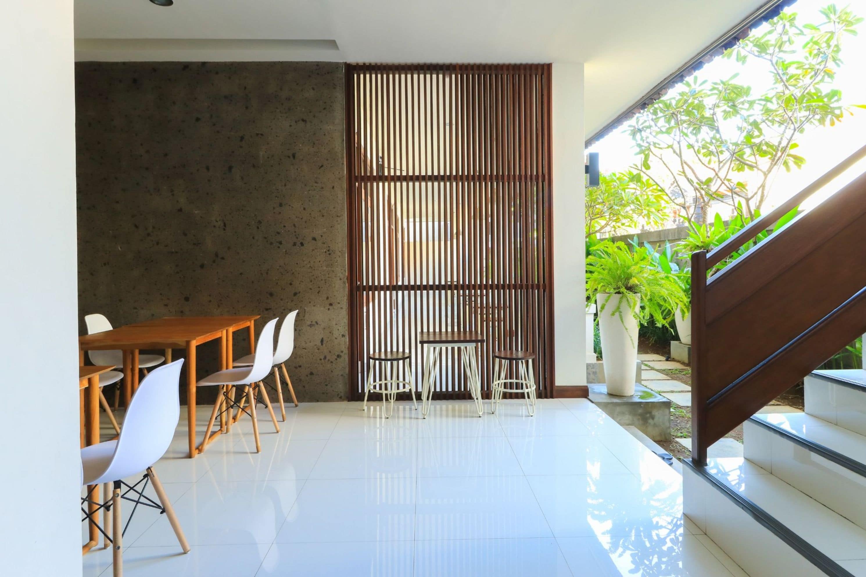 A modern interior with a dining area, a staircase, and a view of greenery outside.