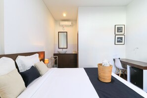 A hotel room with a bed, a desk, a chair, a sink, and a mirror. - Kak Garden Inn by Zuzu (Kuta)