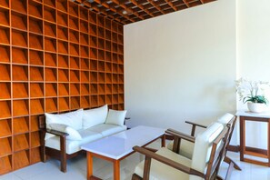 Una habitación moderna con un muro de listones de madera, un sofá blanco, una mesa de centro de vidrio y sillas de madera.