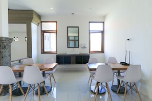 A conference room with a long table and six chairs, a stone pillar, and two windows with curtains. - Kak Garden Inn by Zuzu (Kuta)
