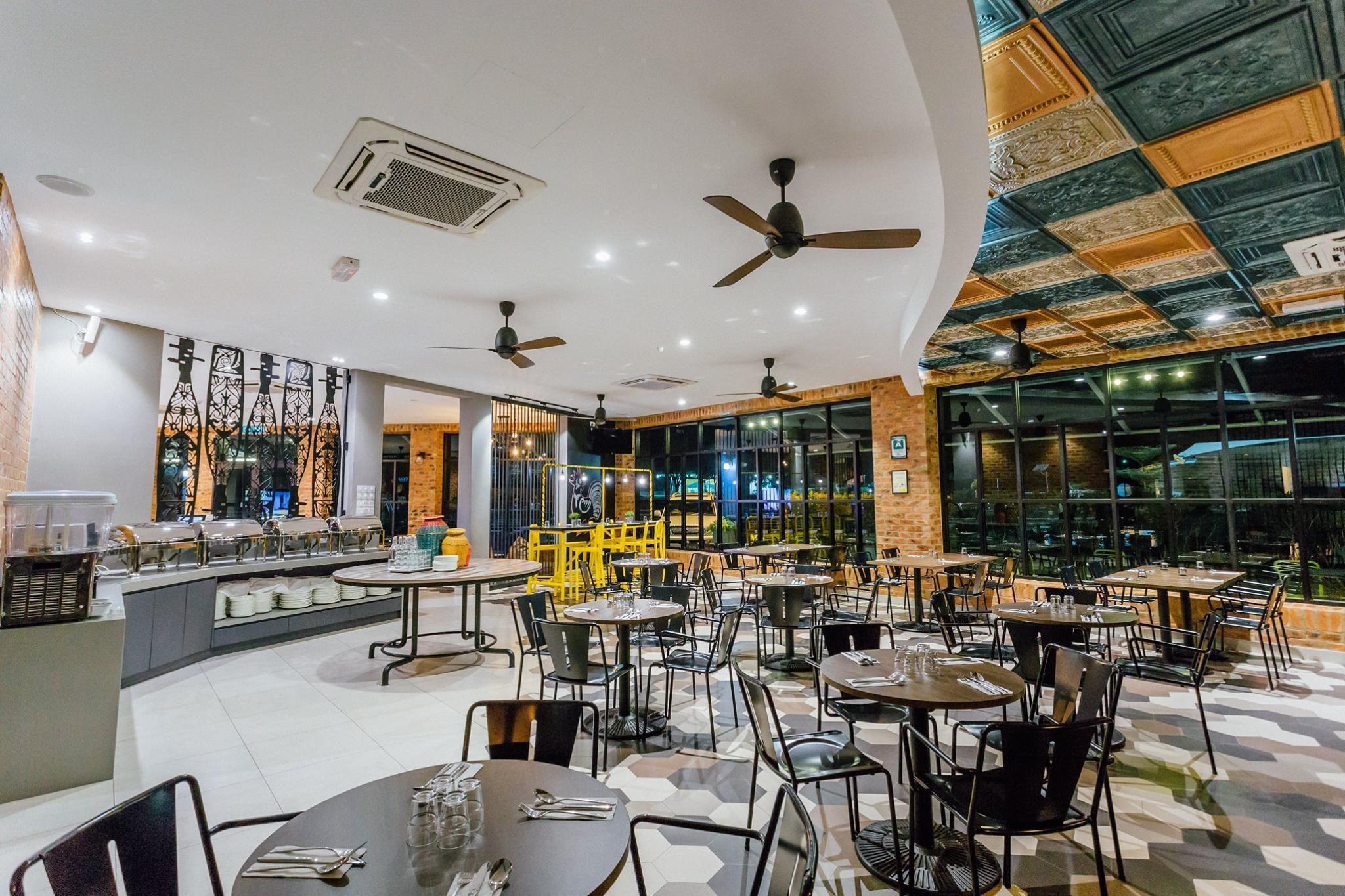 Un restaurante con varias mesas y sillas, ventiladores de techo y una zona de bar.