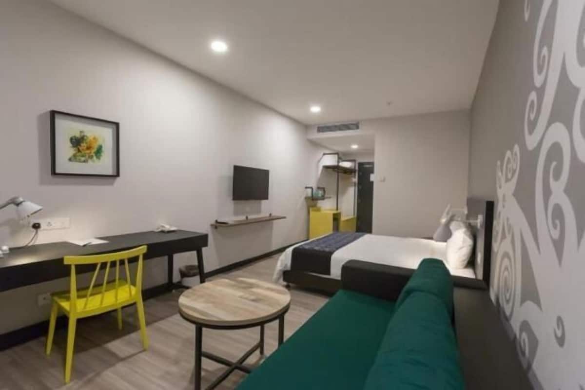 Una habitación de hotel moderna con una cama, un escritorio, una silla y una mesita.