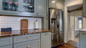 Une cuisine avec des meubles de couleur bleu clair, un réfrigérateur en acier inoxydable et un plan de travail en bois.