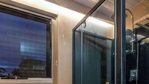 Ein modernes Badezimmer mit einer Duschkabine, einer Toilette und einem Fenster mit Ausblick.