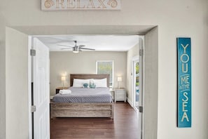 A bedroom with a bed, bedside tables, a ceiling fan, and a wall sign. - The Pompano Beach House 🏖️ Heated Pool & Spa | 1 Mile to Beach (Pompano beach)