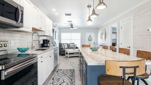 A modern kitchen with white cabinets, a stainless steel stove, and a large island with bar stools. - Waterfront, oceanview renovated pvt. 3 bedroom, 3.5 bath with pool and dockage. (Marathon)