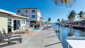 A waterfront property with a pool, lounge chairs, and a dock with boats. - Waterfront, oceanview renovated pvt. 3 bedroom, 3.5 bath with pool and dockage. (Marathon)