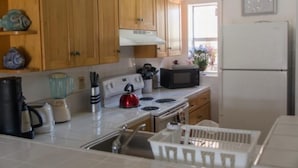 Una cocina con gabinetes de madera, estufa, microondas y refrigerador.