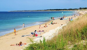 A beach with people sunbathing and swimming.