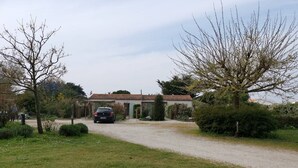 A gravel driveway leading to a building with a tiled roof. - Cottage Les Roses de mer ( Les Agapanthes ) (Sainte Marie de Ré)