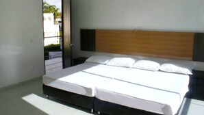 Une chambre moderne avec un lit double, une tête de lit en bois et une vue sur l’extérieur.