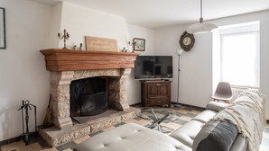 A living room with a stone fireplace, a television, a sofa, and a window with curtains.