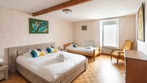 A hotel room with two beds, a wooden ceiling, a window, and a chair.