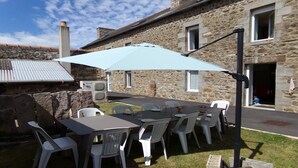 An outdoor patio with a table and chairs, a stone building in the background, and a clear sky.
