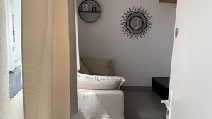 Een slaapkamer met een bed, een gordijn, een spiegel aan de muur en een zonachtige decoratie.