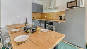 A modern kitchen with a wooden table set for dining, a microwave, a stove, and a refrigerator.