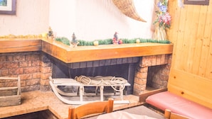 A cozy room with a fireplace, a wooden bench, and a small table. - Hotel Milano (Valfurva)