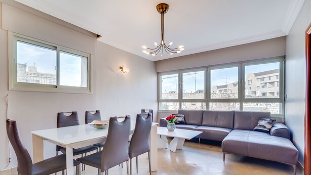 Ein modernes Wohnzimmer mit Essbereich, großen Fenstern und Blick auf die Stadt.