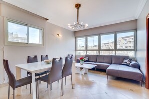 Een moderne woonkamer met een eethoek, grote ramen en uitzicht op de stad.