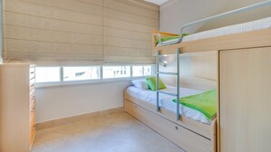 Ein Schlafraum mit Etagenbetten, einem Fenster, einem Holzschrank und einem Schreibtisch.